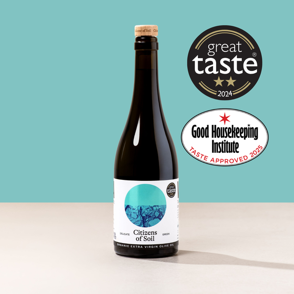 Bottle of greek extra virgin olive oil with 'Great Taste' and 'Good Housekeeping Institute' logos on a teal background
