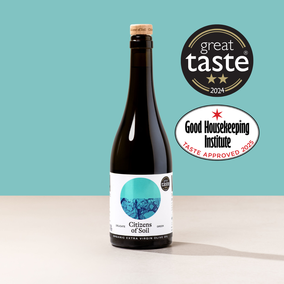 Bottle of greek extra virgin olive oil with 'Great Taste' and 'Good Housekeeping Institute' logos on a teal background