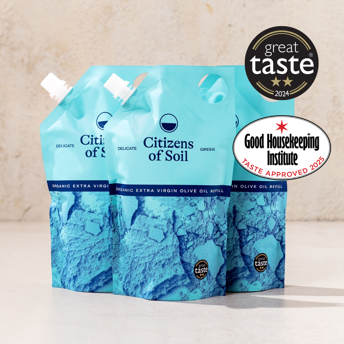 Three blue greek olive oil pouches with certification logos on a beige background